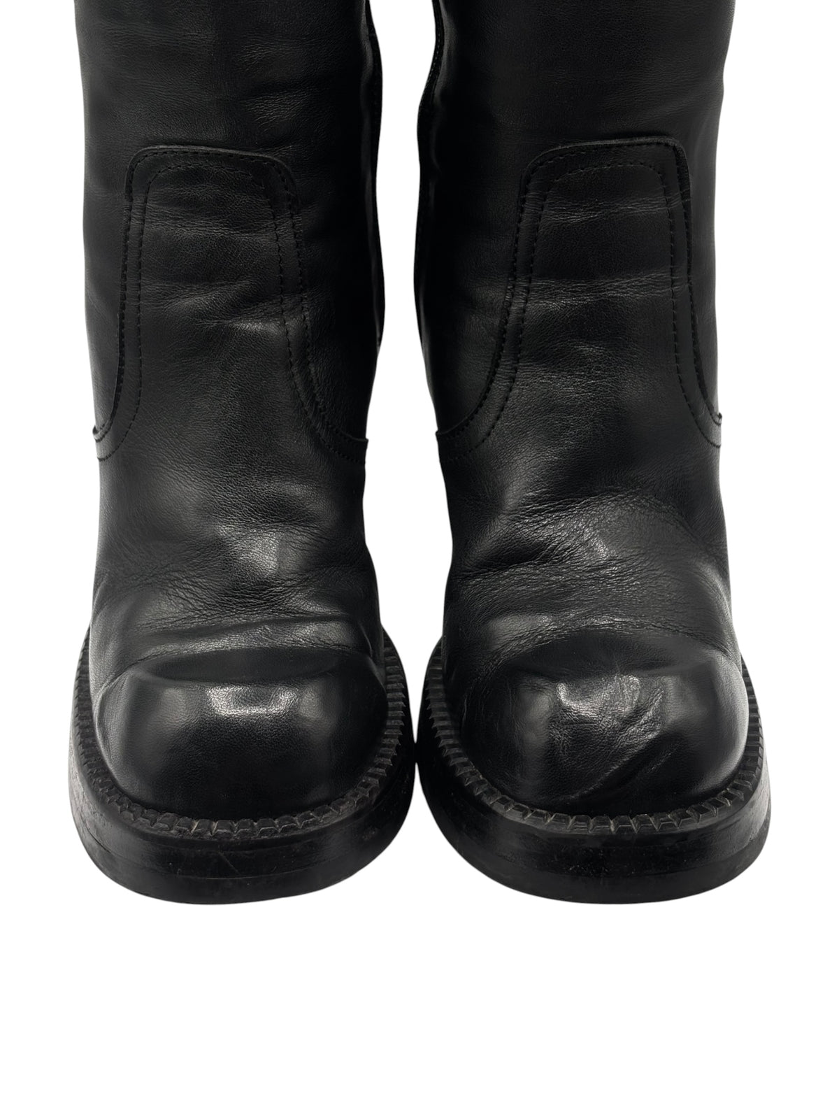 Black knee-high leather boots with rear stitch detailing and thick block heel bottoms.