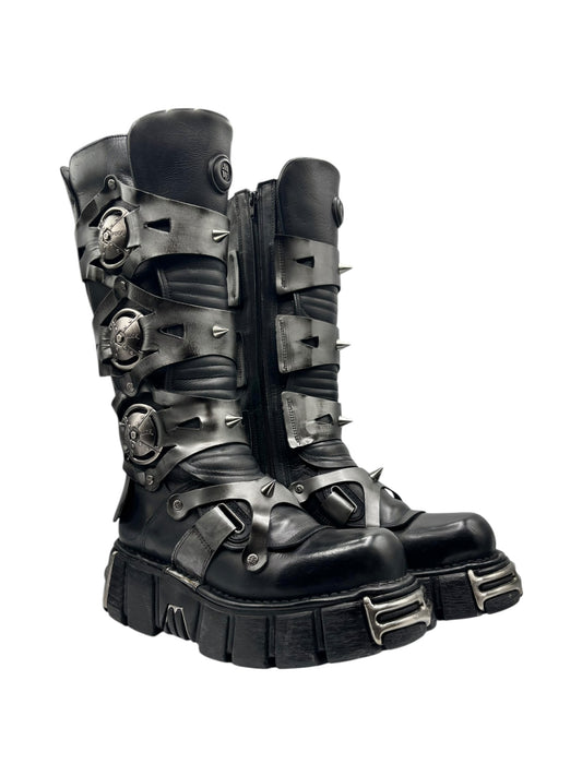 Black knee-high boots with buckle straps, metal studs, and chunky tread sole
