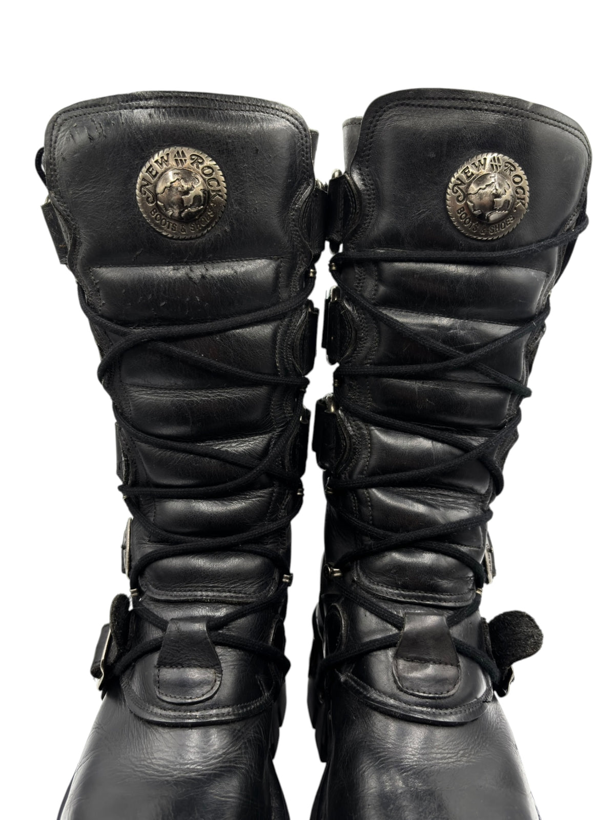 Pair of black knee-high lace-up leather boots with stitched straps and buckles