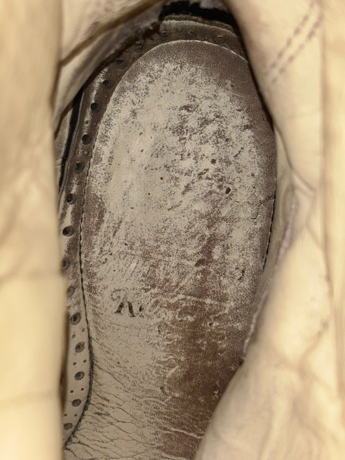 Vintage boot insole close-up with worn texture and embossed branding
