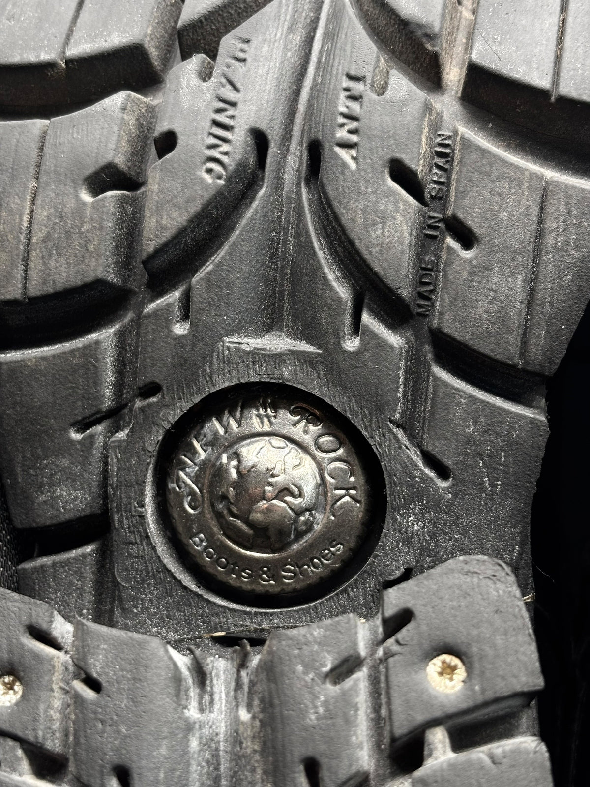 Boot outsole tread detail with raised circular logo and “Made in Spain” text.