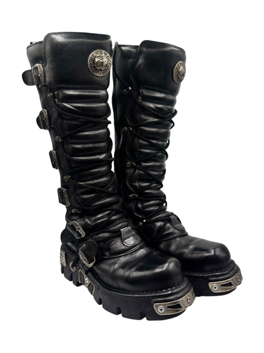 Angled view of black knee-high leather boots with ruched laces and chunky lug sole
