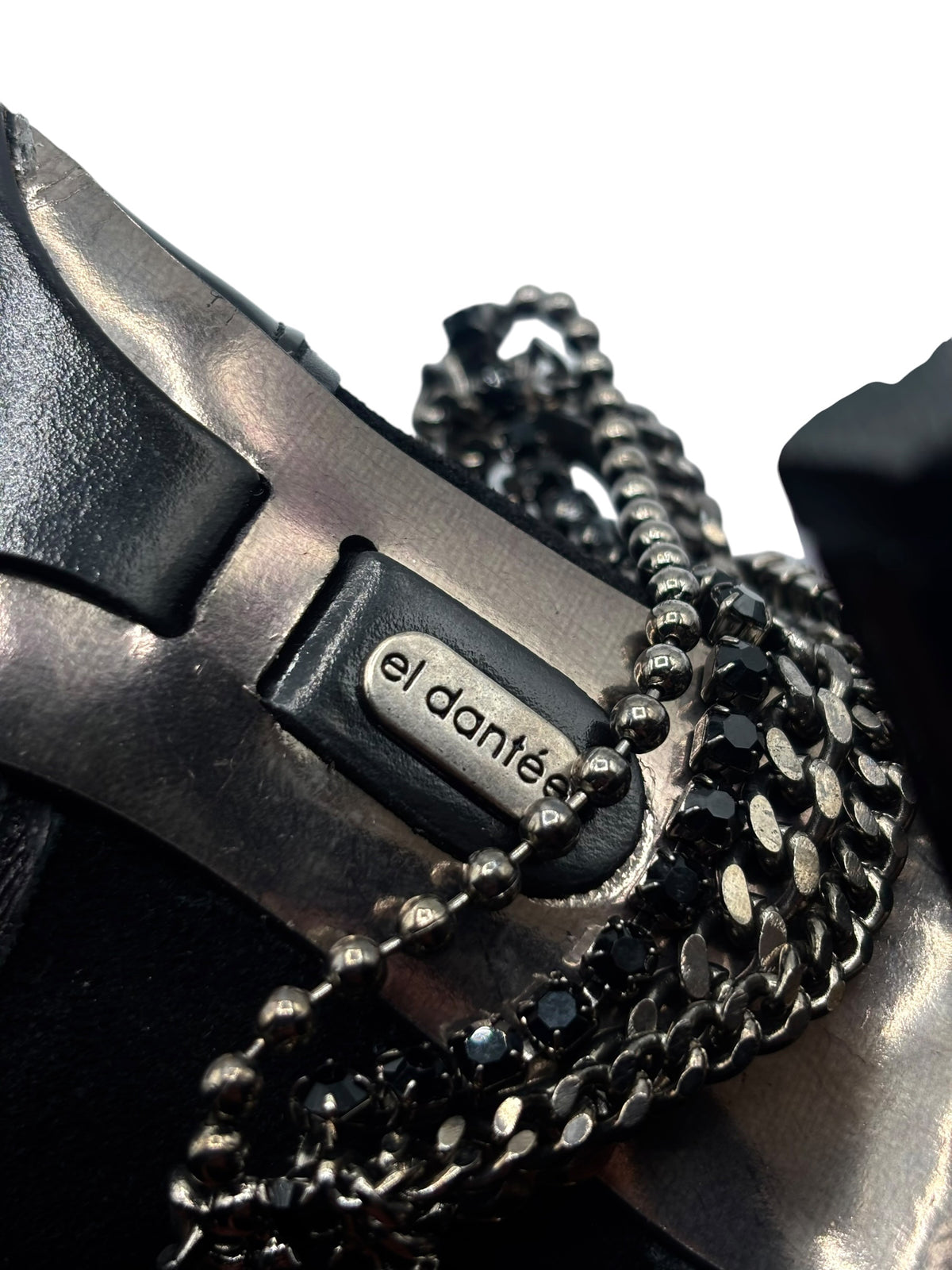 Close-up of black boot heel and chain-embellished strap detailing