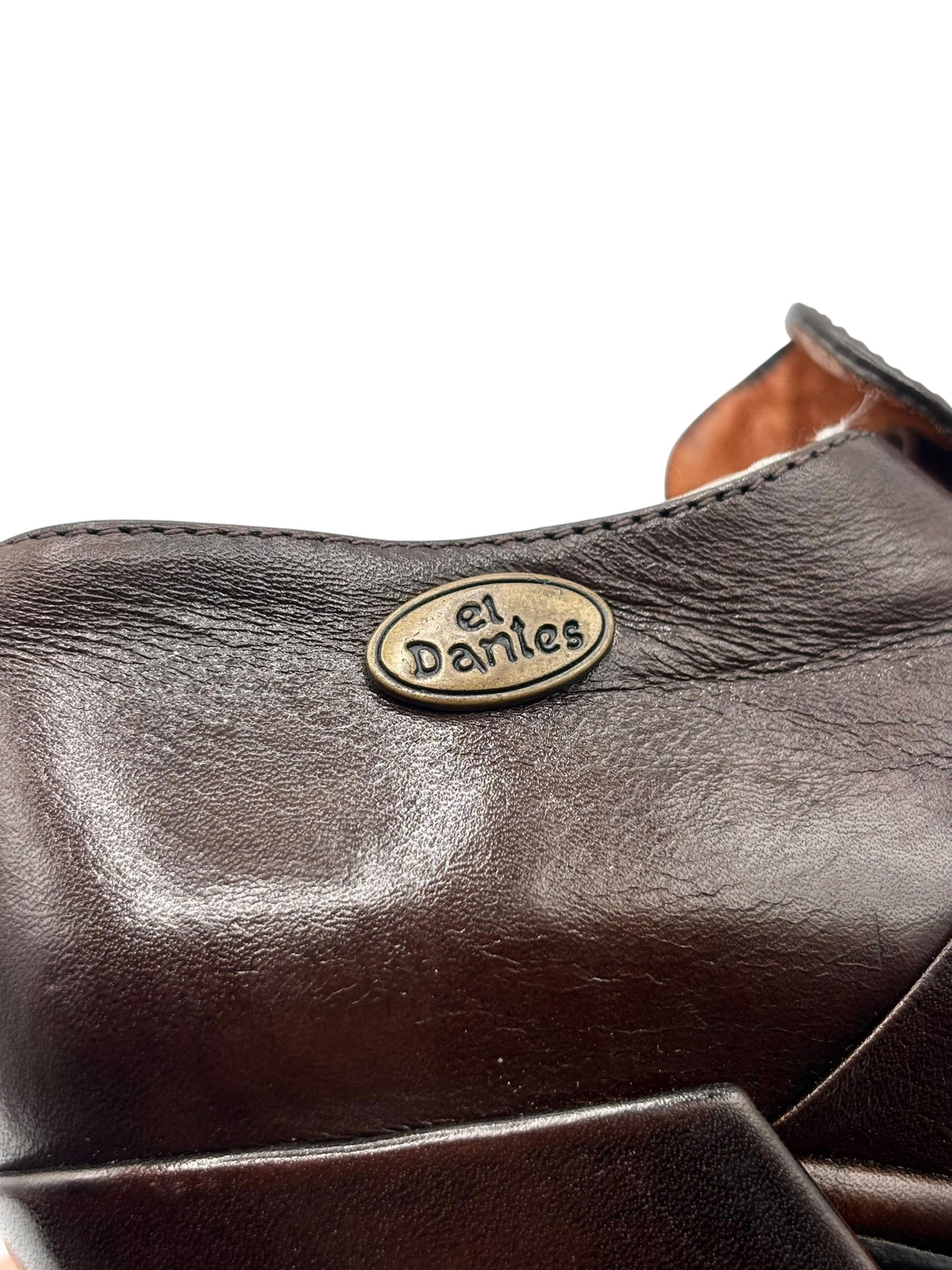 Dark brown leather heel shoe close-up with circular Dantes logo on strap