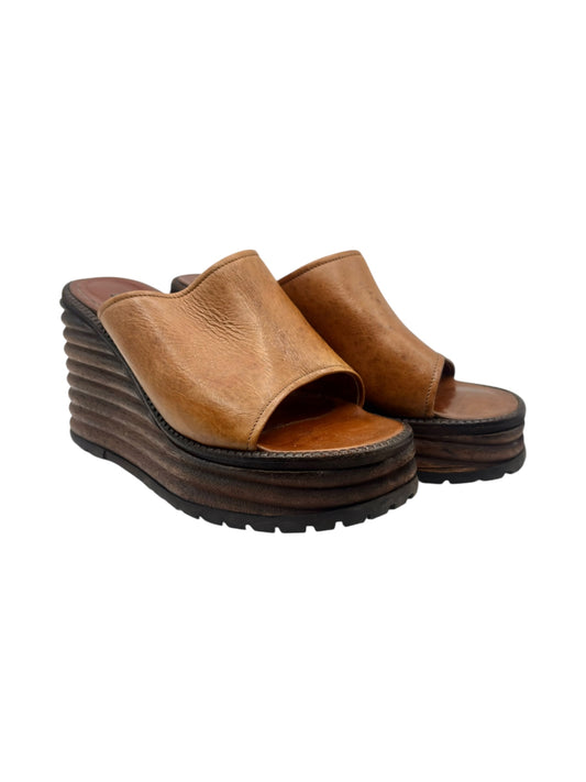 Brown leather platform slide sandals with two straps and chunky tread sole.
