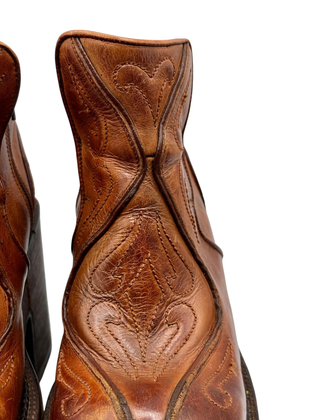 Close-up of brown leather boot upper with embossed bird-like stitching detail