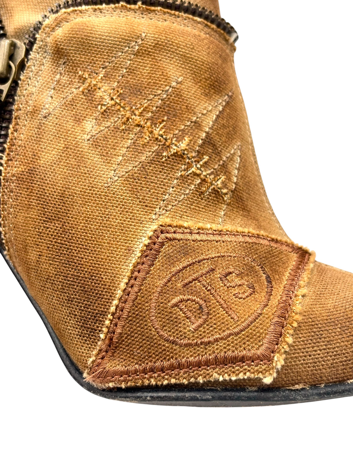 Close-up of tan outer panel with stitched emblem patch and rugged edge trim