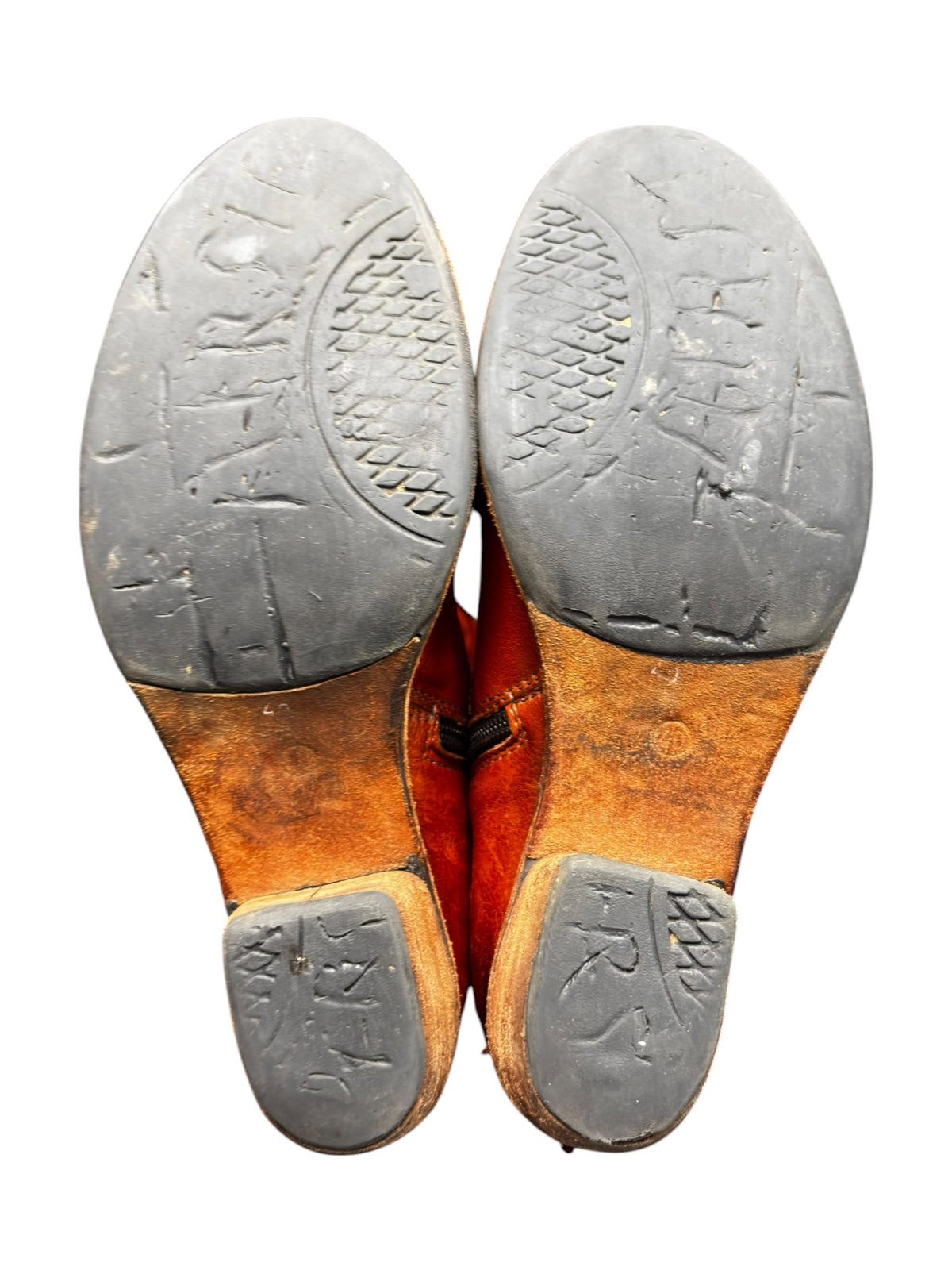 Vintage leather boots with worn rubber soles, pair view from the bottom