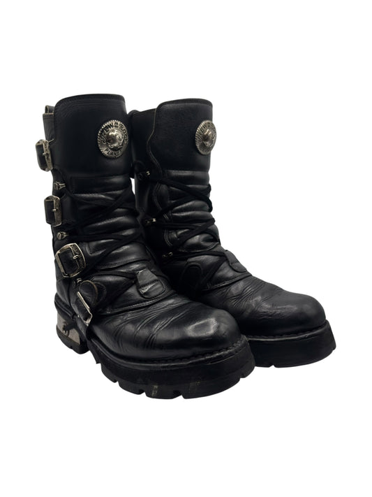 Black mid-calf leather lace-up boots with buckled straps and raised heel, side view