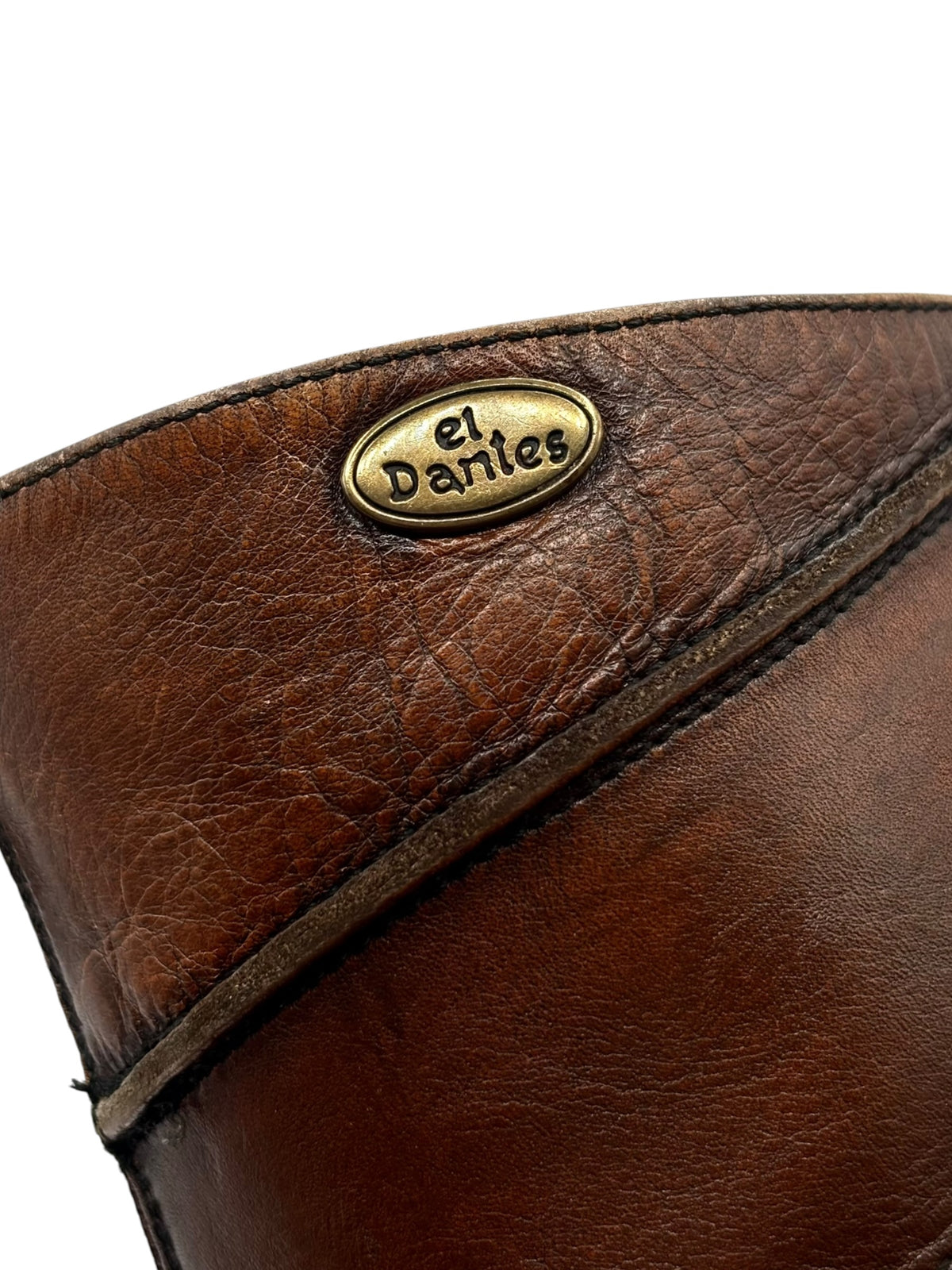 Close-up of "el dantes" logo patch on brown boot upper near the top edge.