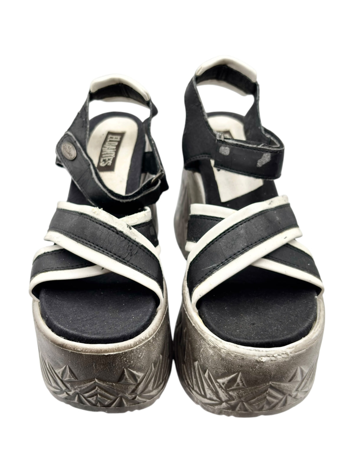 Front view of black platform sandals with white straps and textured silver sole