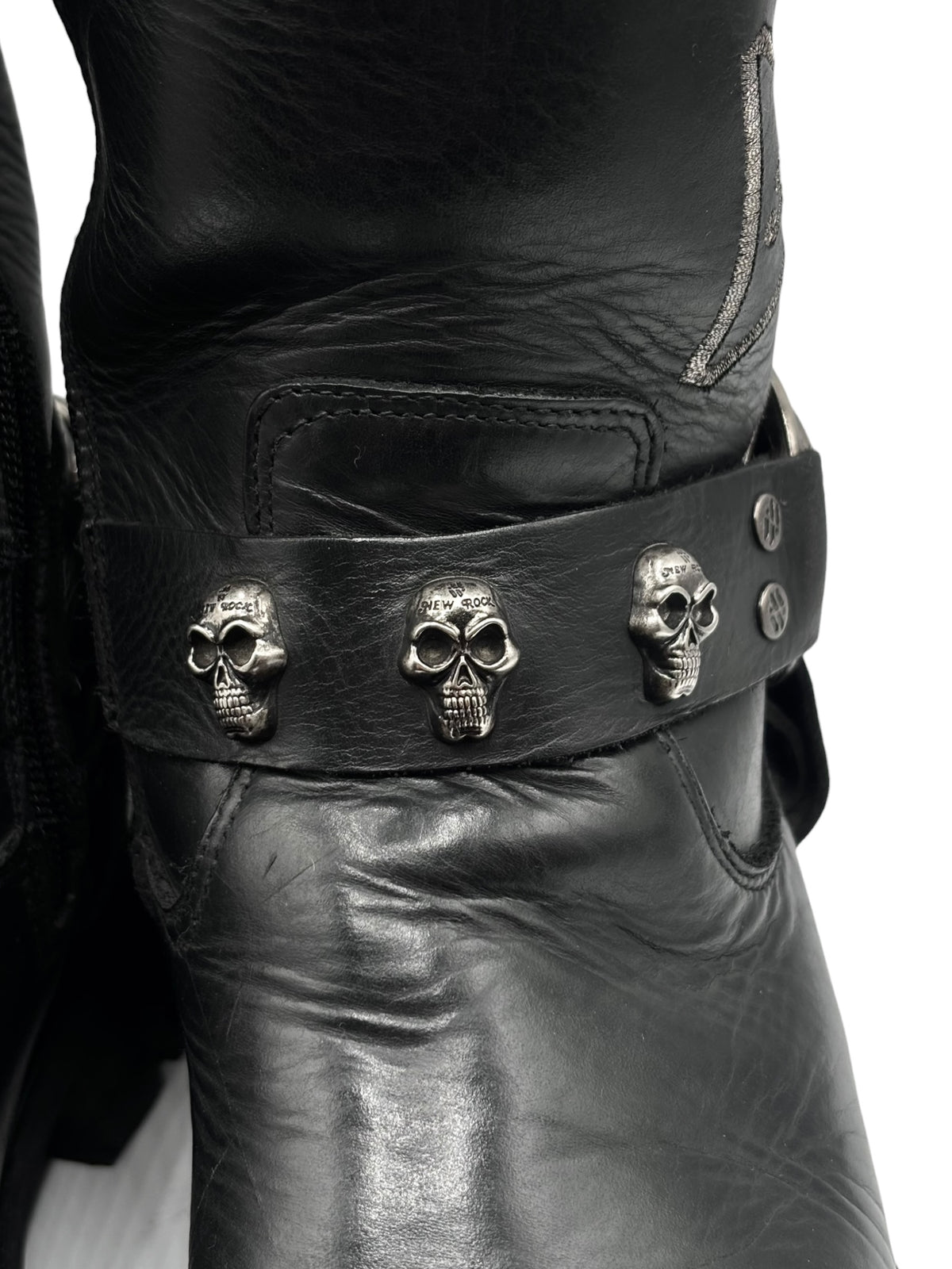 Black leather biker boots: close-up studded ankle strap with skull charms