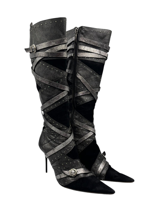 Black leather tall boots with crisscross straps, buckle accents, and stiletto heel