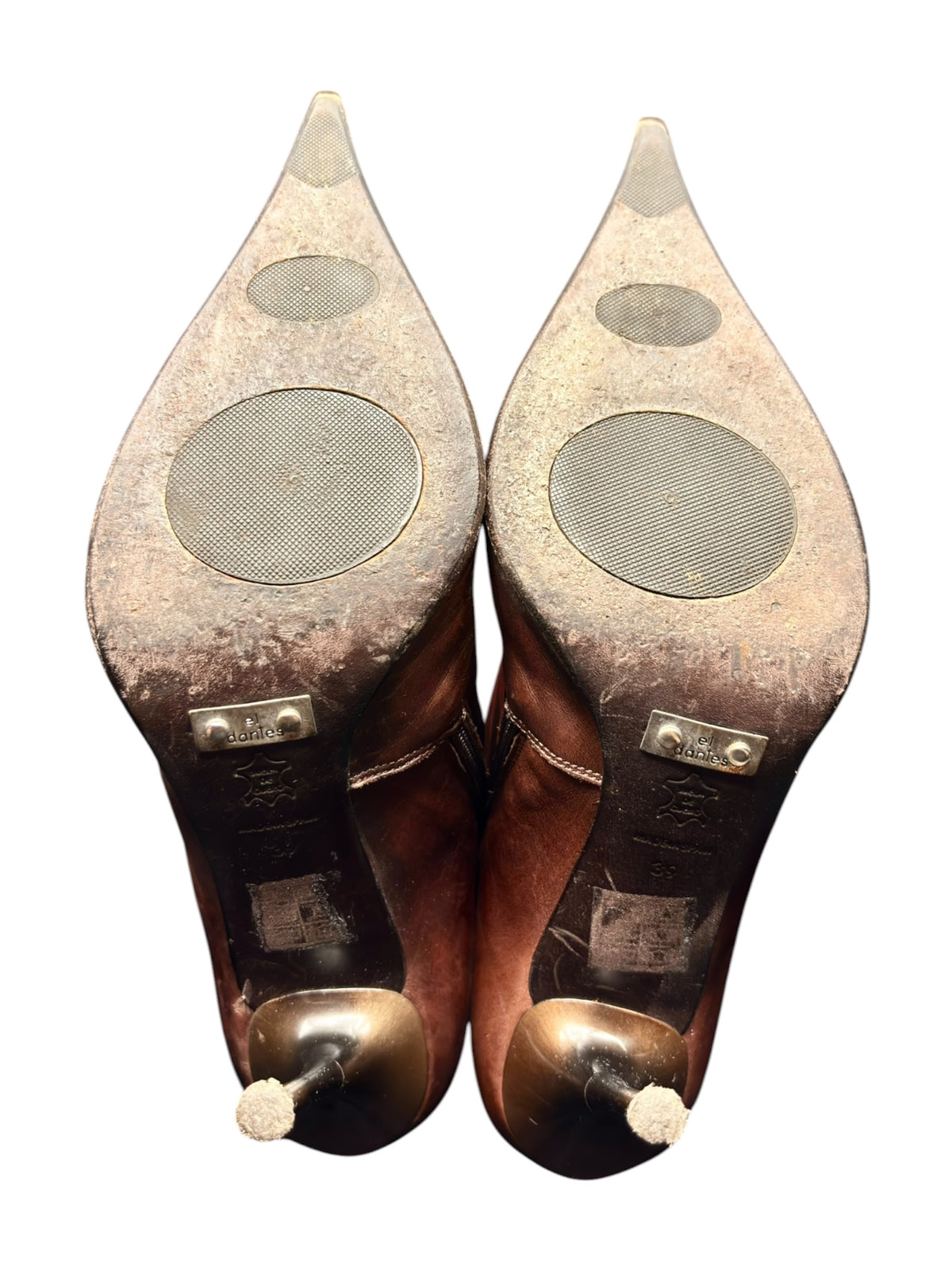 Pair of knee-high leather boots shown from bottom with circular wear marks