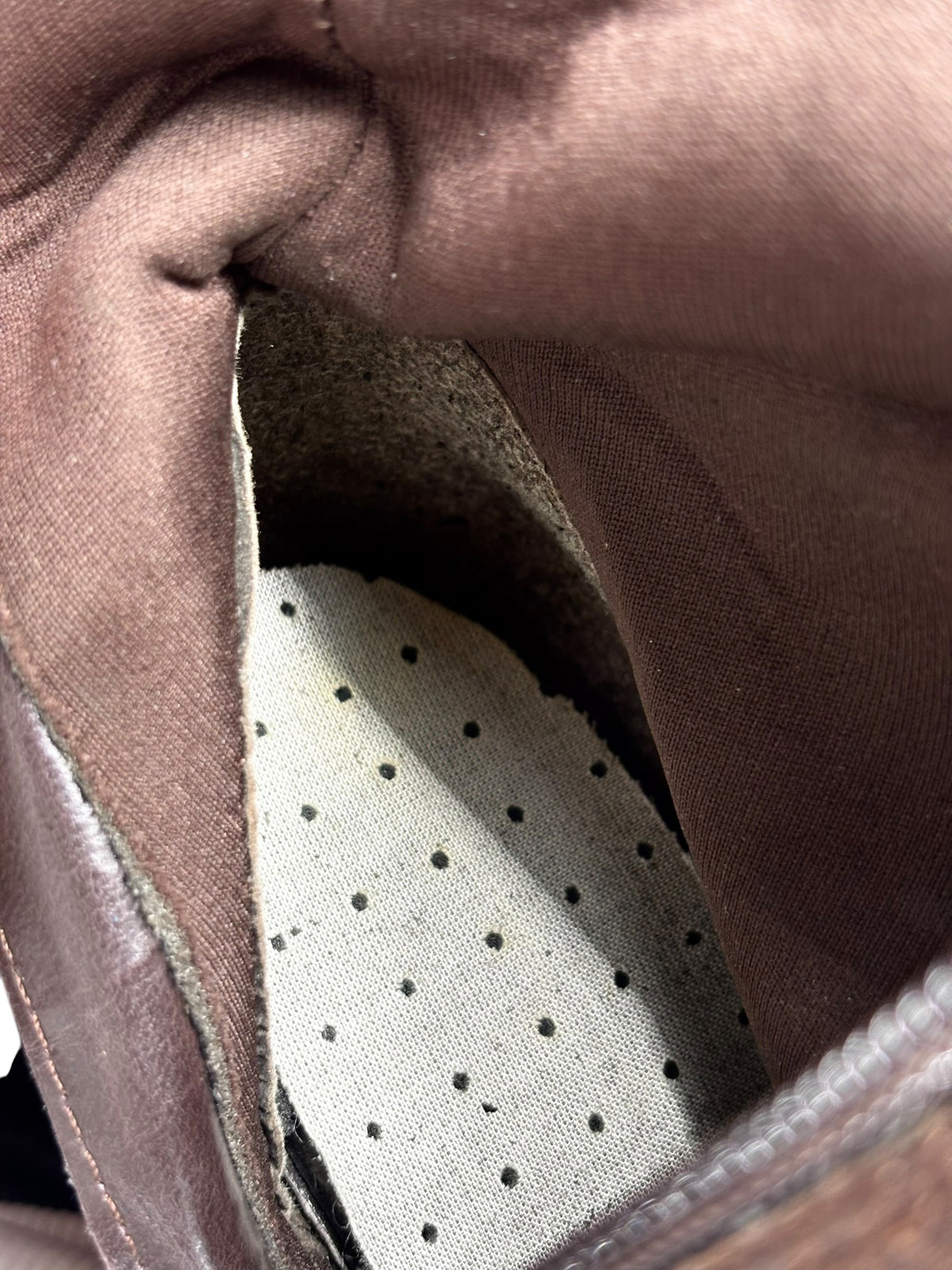 Knee-high patchwork boots with perforated lining detail at the opening.
