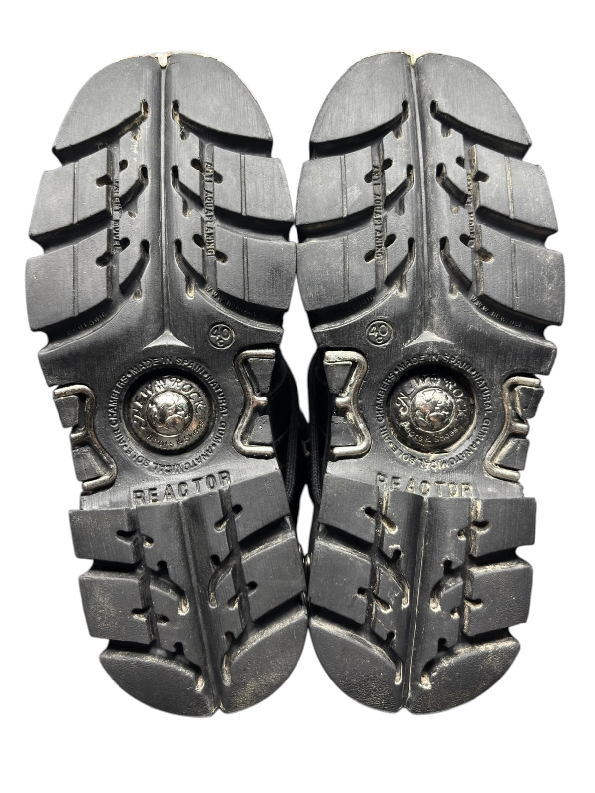 Pair of knee-high boots, view of rugged sole tread and circular logo plate
