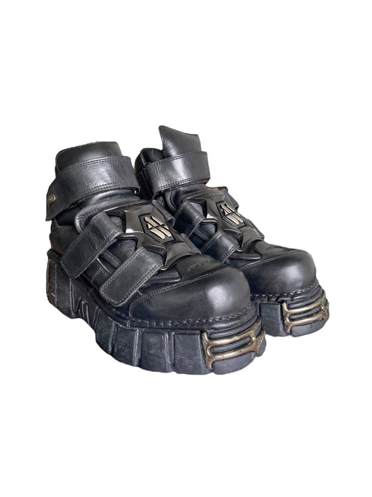 Black leather platform boots with hook straps, metal trims, and chunky tread outsole