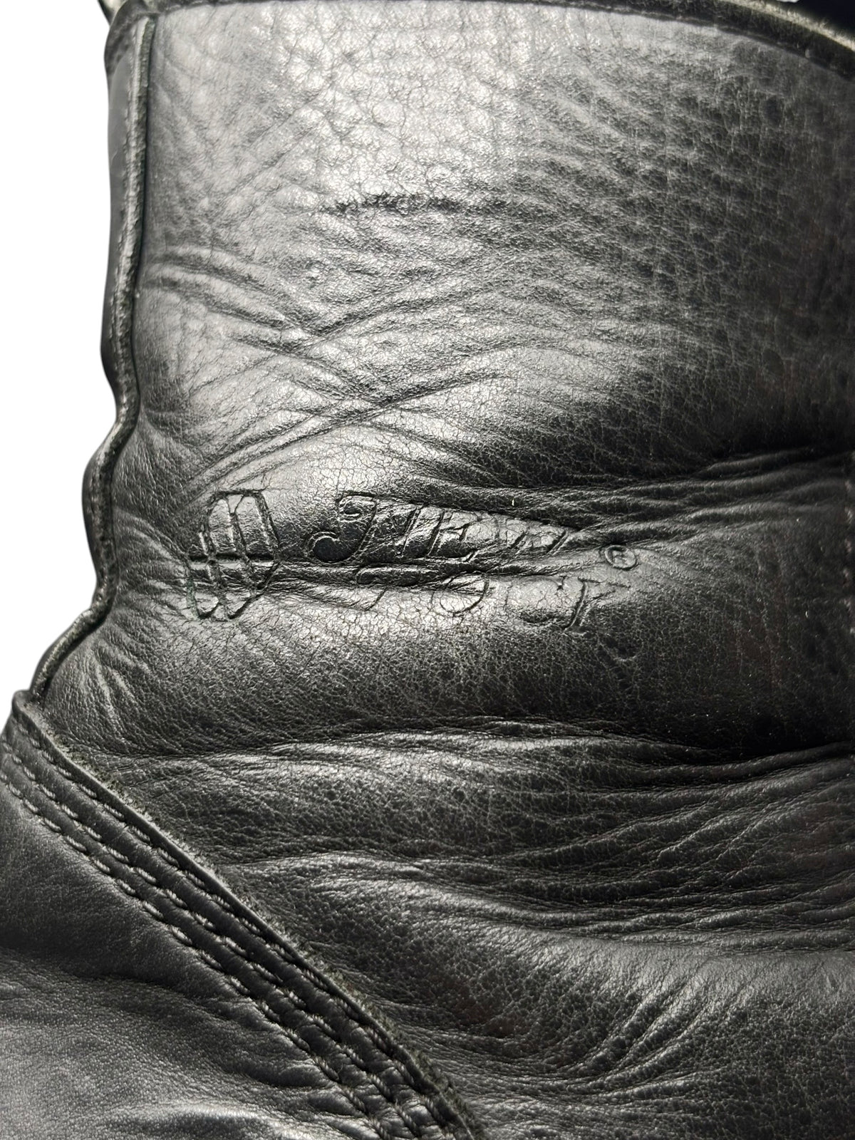 Close-up of black boot leather upper with stitched panels and textured finish.