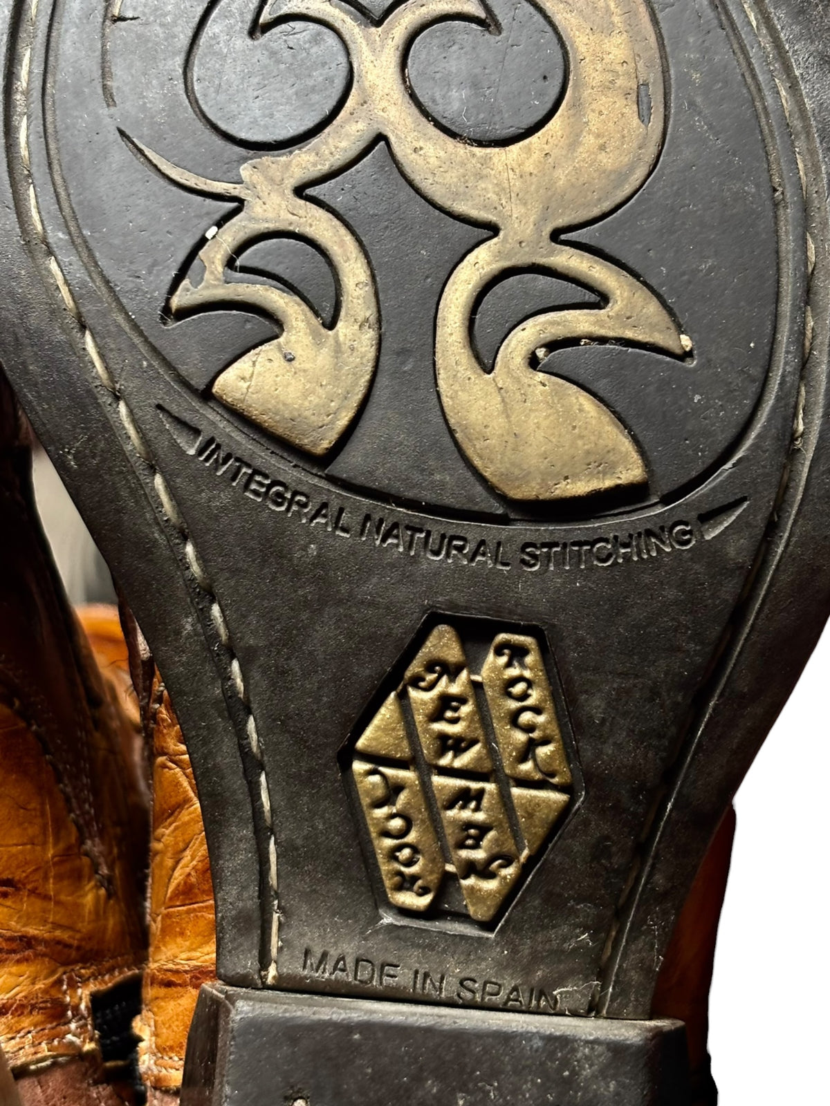 Close-up of boot outsole with ornate logo and "MADE IN SPAIN" text