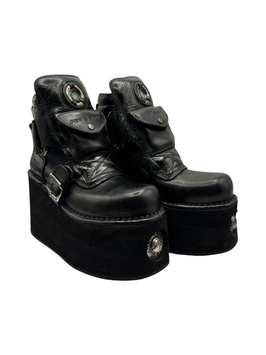 Black platform pouch boots with buckle strap, top eyelets, and stitched toe