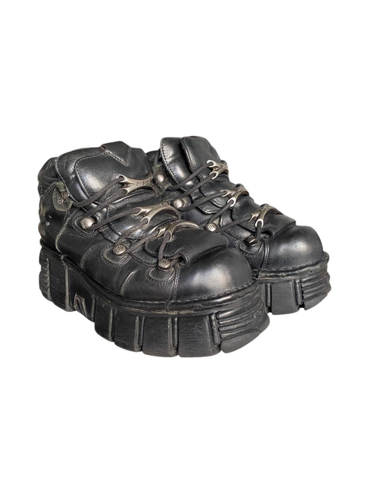Black leather platform boots with chunky lug sole, lace-up closure and side straps.