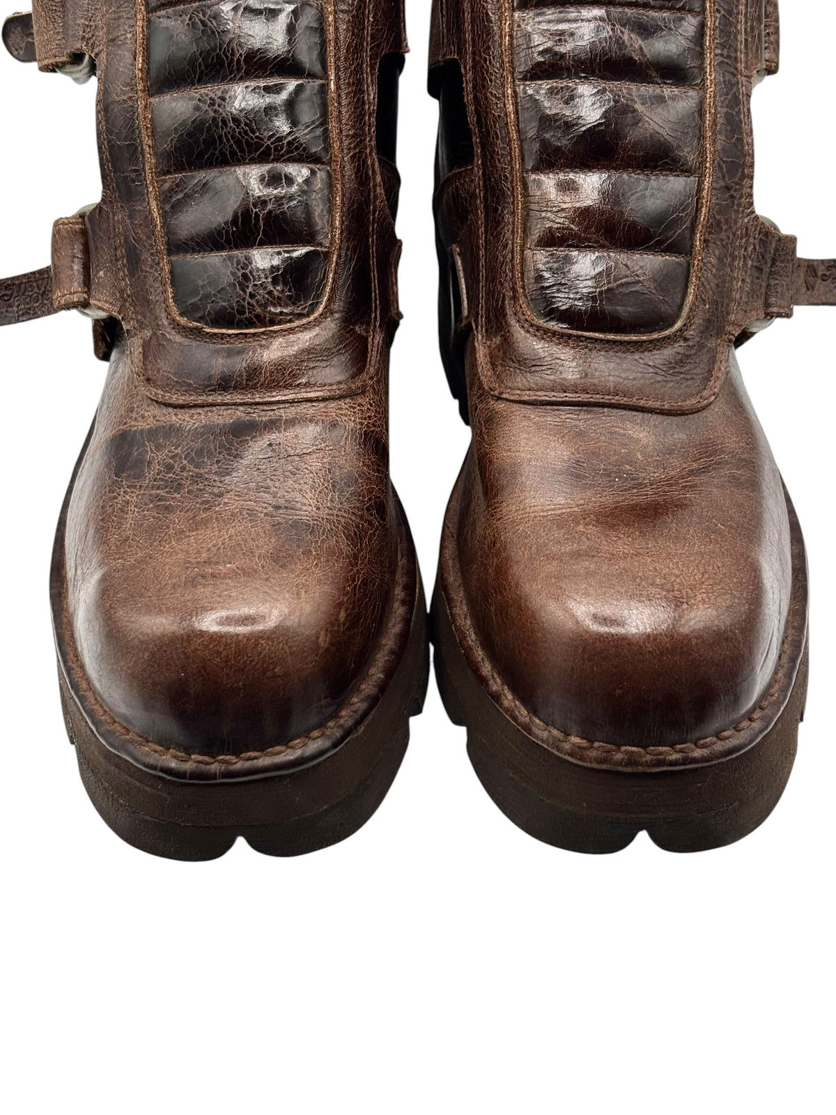 Brown distressed leather ankle boots with side panels, straps, and lug soles