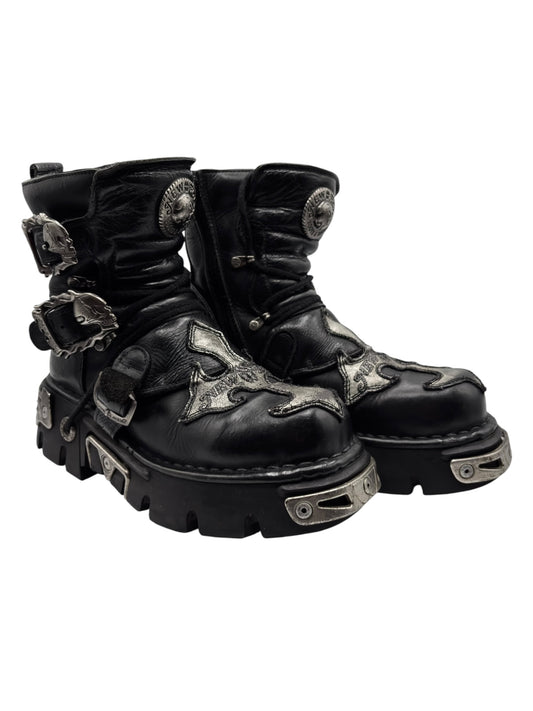 Angled view of black leather lace-up platform boots with decorative metal strap hardware