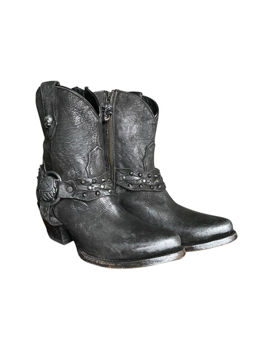 Dark leather cowboy boots angled view, studded strap and zipper at the shaft center.