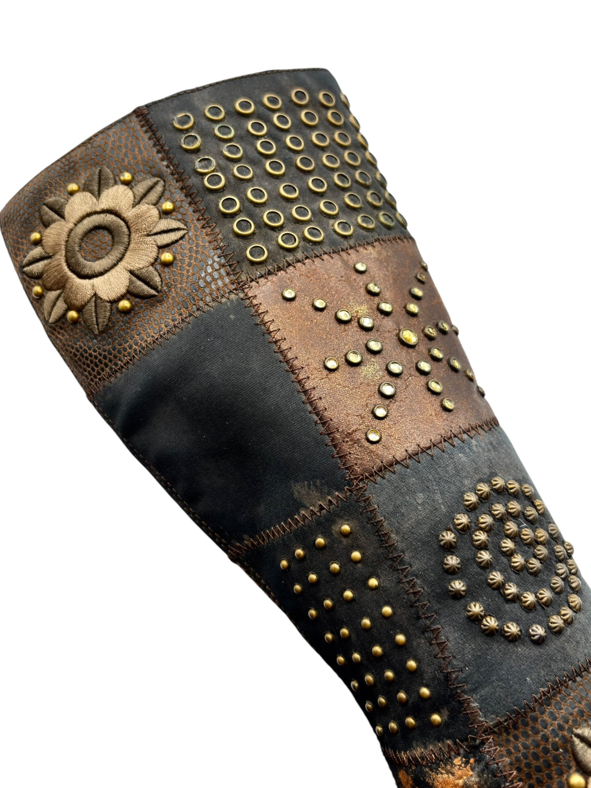 Close-up of knee-high boots showing multi-panel patchwork and gold stud embroidery.
