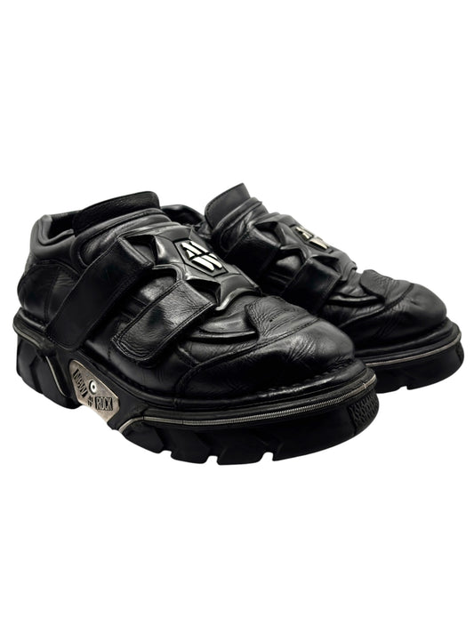 Black leather platform boots with chunky sole and metal logo on straps