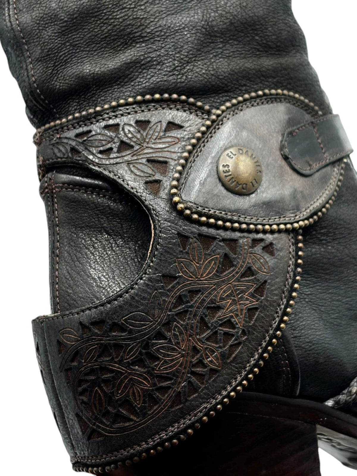 Vintage knee-high leather boots close-up of embossed floral panel and small buckle strap
