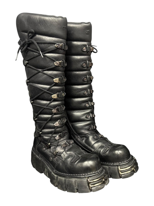 Black leather lace-up boots with buckled straps and padded shaft, thick tread sole.