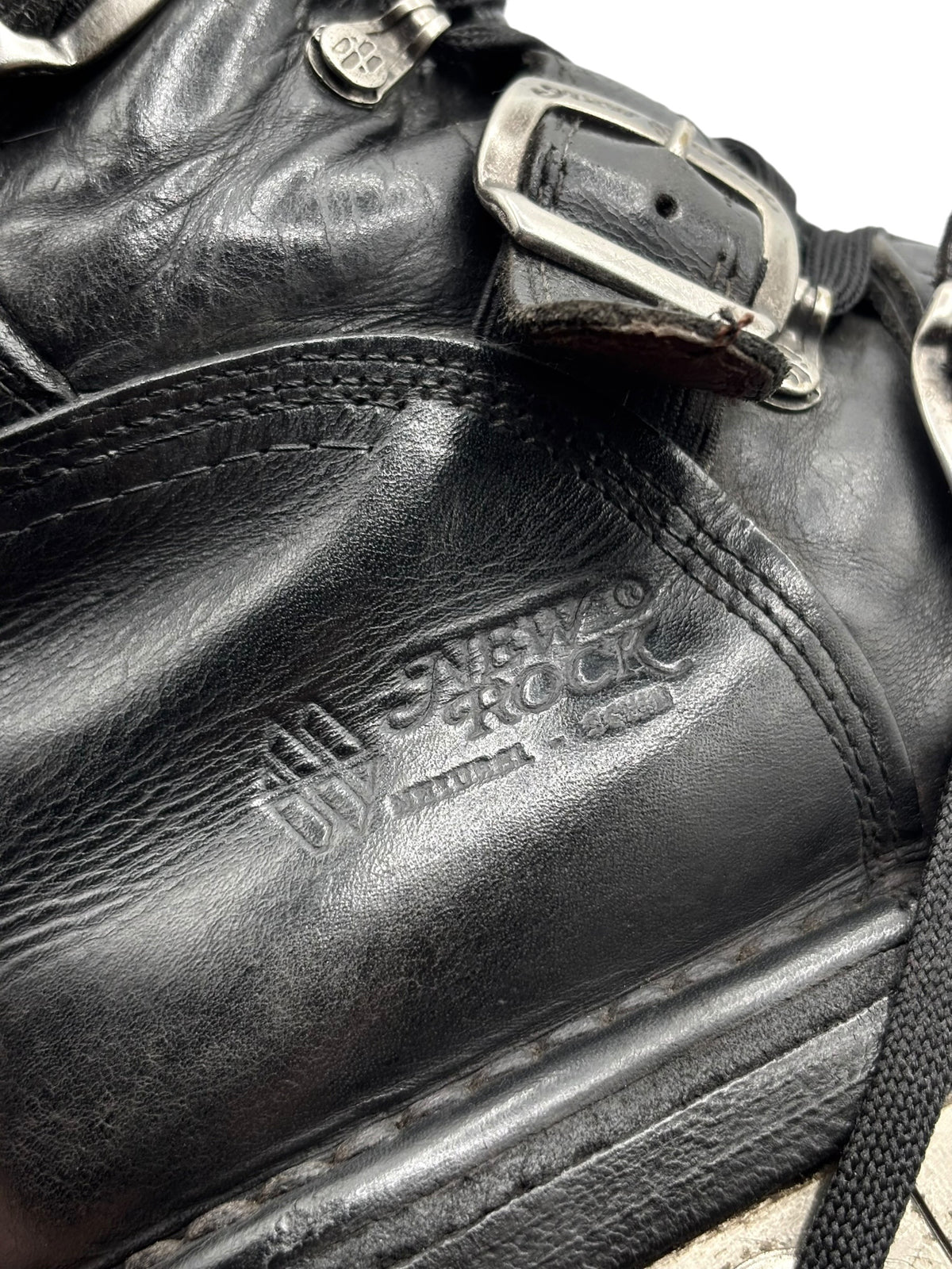 Black leather boot upper close-up with embossed logo and stitched seam