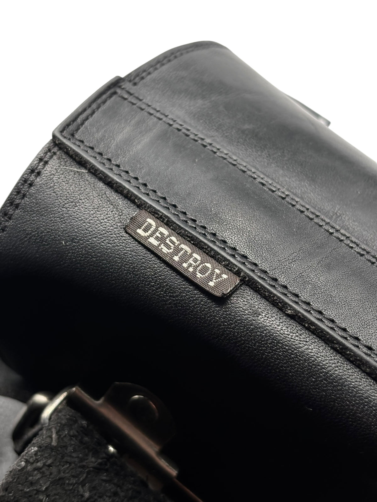 Leather boot upper close-up with stitched edge and 'DESTROY' logo patch