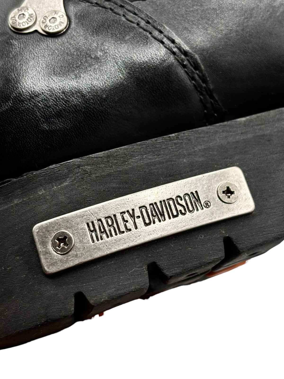 Metal Harley-Davidson logo plate on black leather boot with tread edge