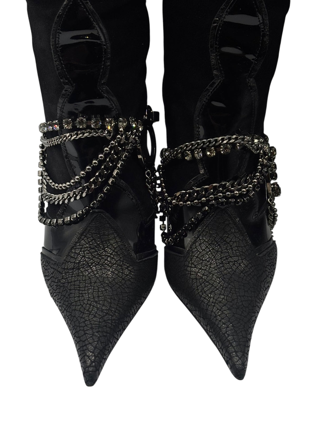 Close-up of black pointed-toe boots with chain ankle bands and rhinestone accents