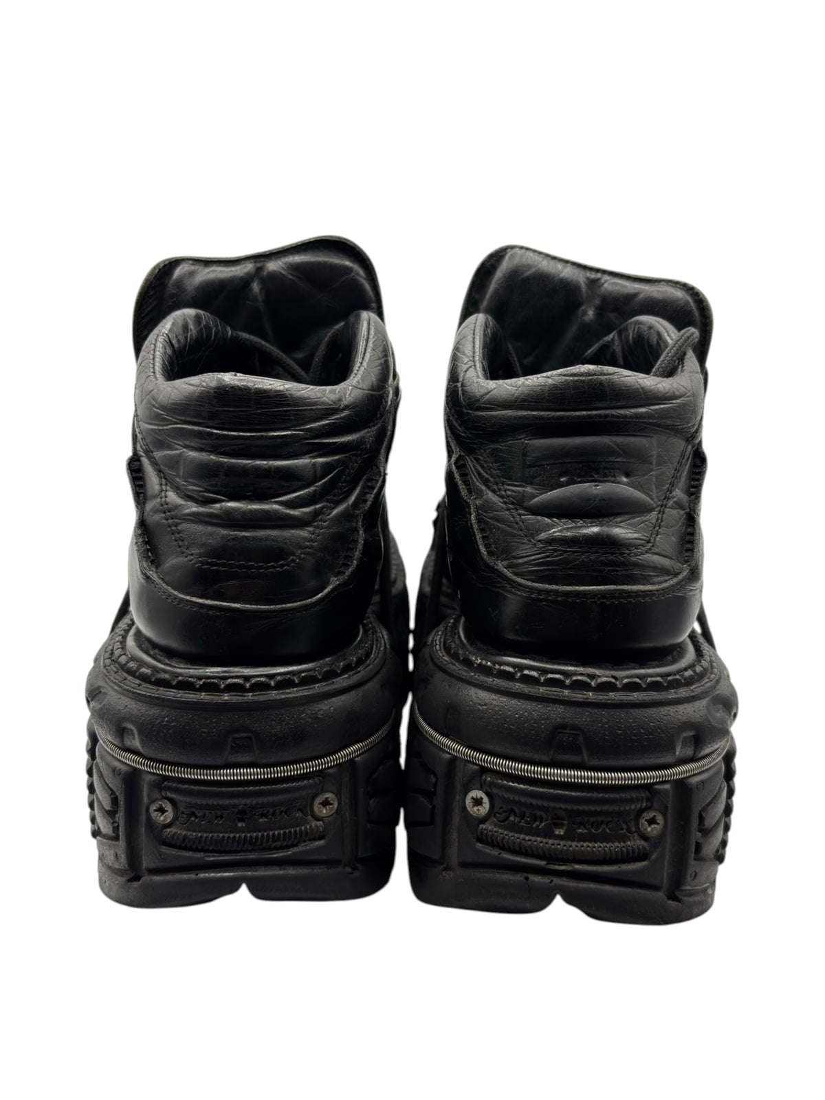 Black platform boots rear view showing collar padding and stacked heel section.