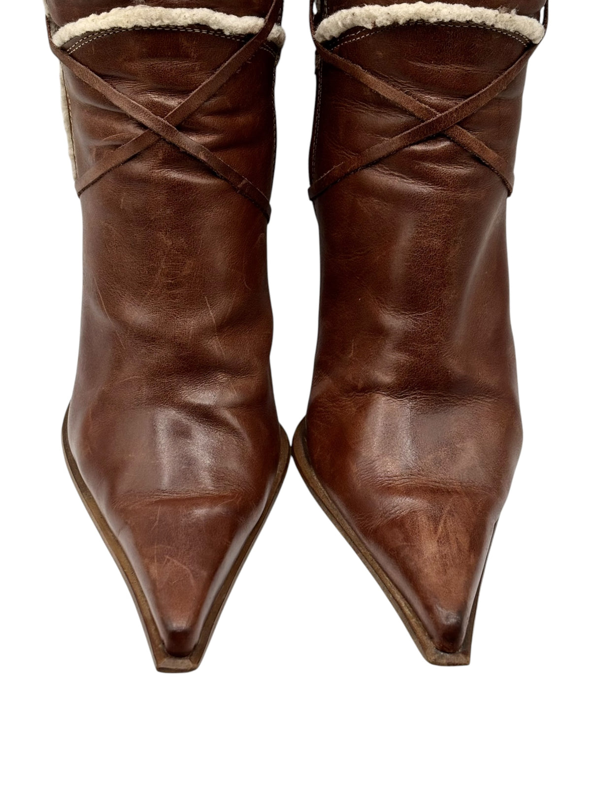 Close-up of brown pointy-toe boots with stitched lines and cream sherpa collar.