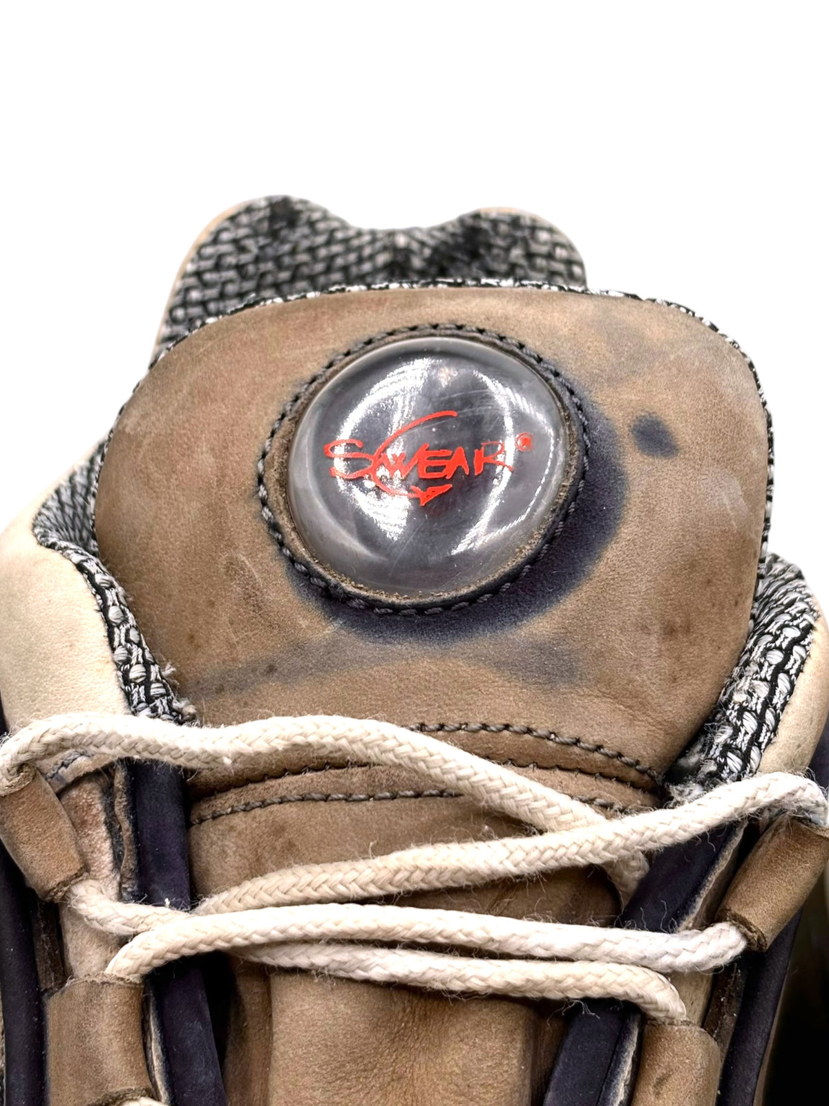 Close-up of Swear logo badge on beige boot heel with stitched leather and laces