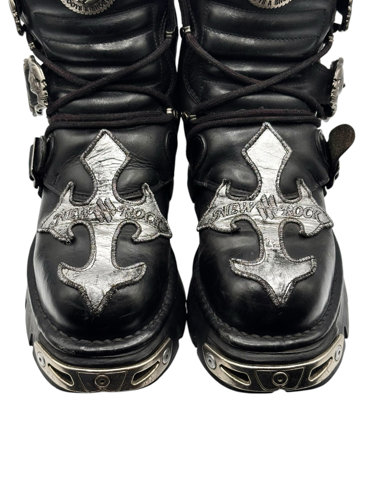 Black lace-up boots with silver cross-shaped patches and studded ankle straps