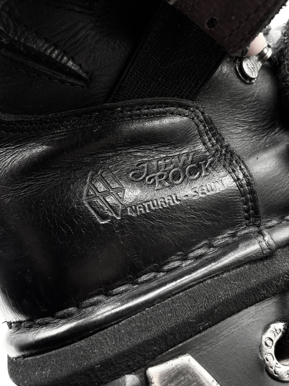 Black leather boot with embossed logo text on side panel near padded collar