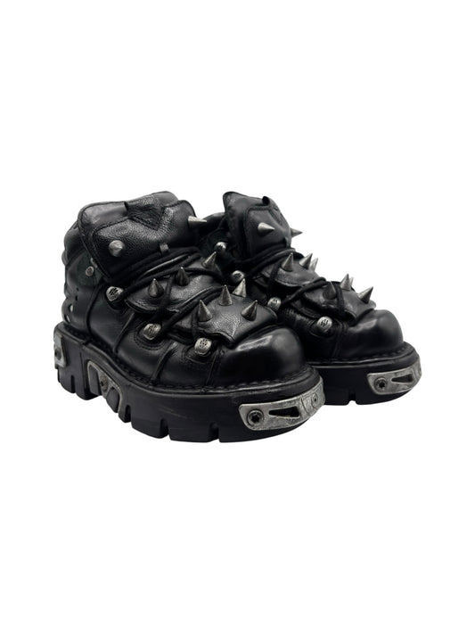 Black leather platform boots with side straps, metal eyelets, and spiked tread sole
