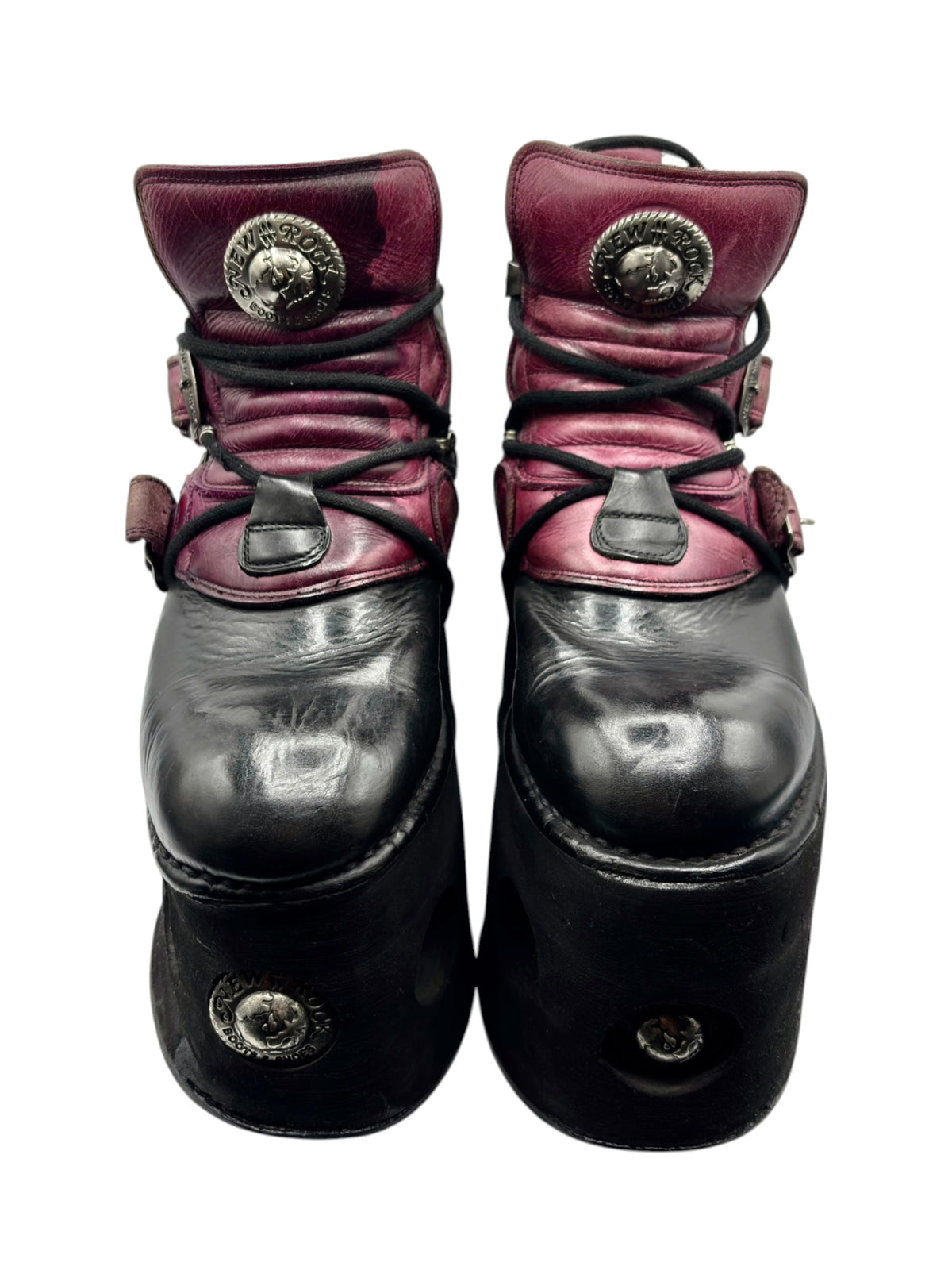 Pair of purple and black platform boots with round metal emblems and lace-up straps