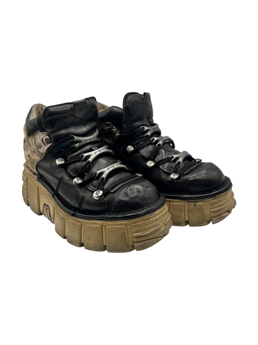 Pair of black lace-up platform boots with tan patterned side panels and chunky tread