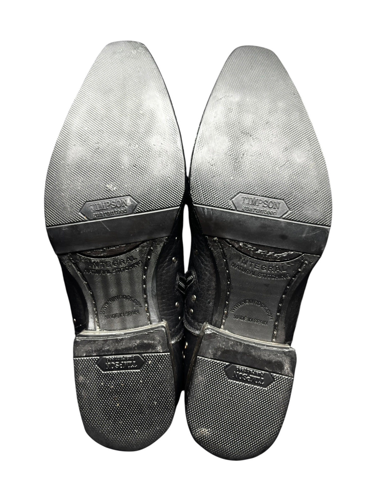 Pair of black studded cowboy boots viewed from bottom, showing textured soles.