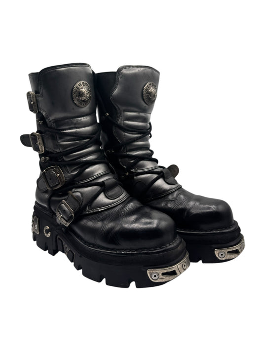 Black leather mid-calf boots with straps, buckles, and thick lug tread