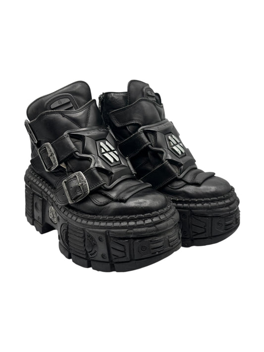 Black techno platform boots with thick lug sole, multiple straps, and metal buckles