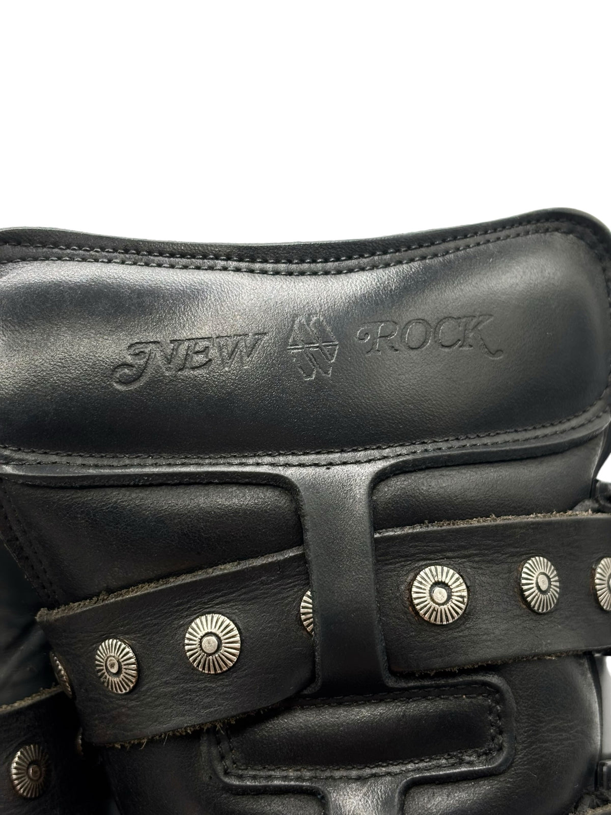 Close-up of black boot shaft with embossed logo and silver ring stud straps