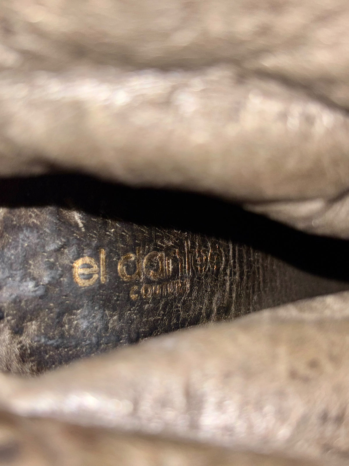 Close-up of inside boot lining with faded brand marking and worn leather