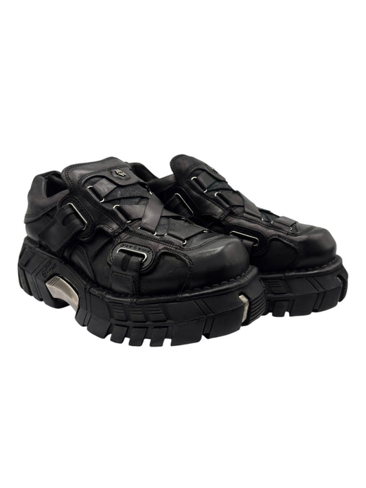 Black platform boots with thick tread sole, side straps, and buckle accents
